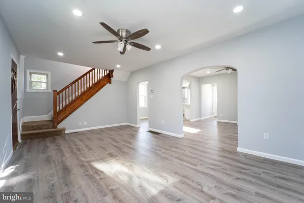 a view of an empty room with wooden floor and a ceiling fan