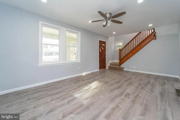 a view of an empty room with wooden floor and a ceiling fan