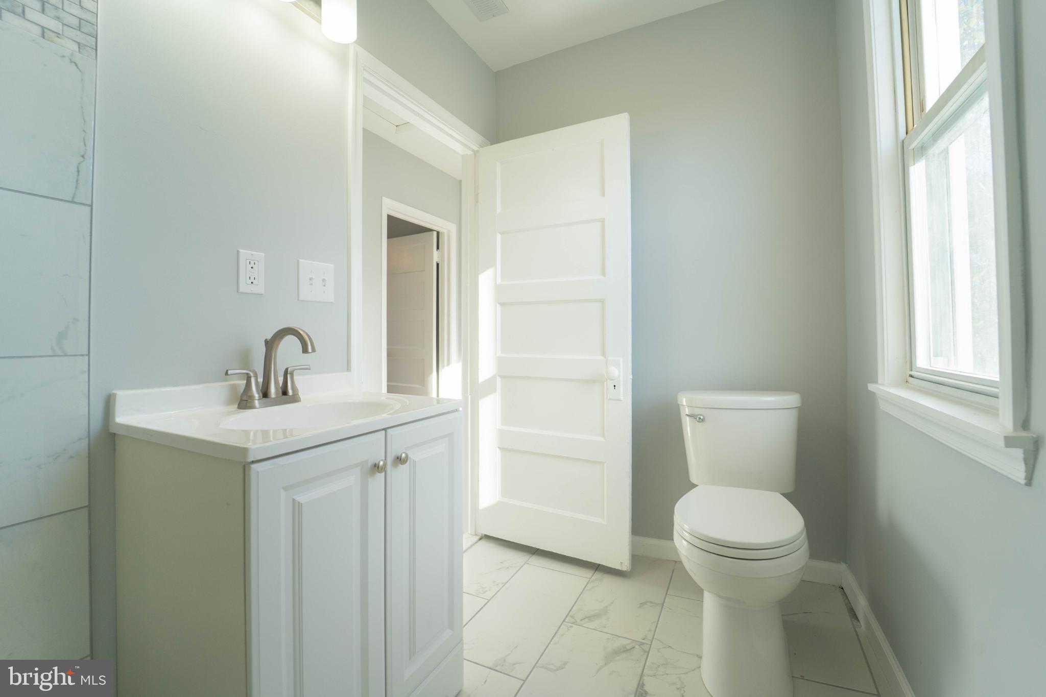 5312 Catalpha Road Baltimore, MD 21214 - Photo 36 of 41 a bathroom with a sink a toilet and a window