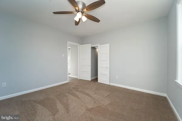 an empty room with closet and a chandelier fan