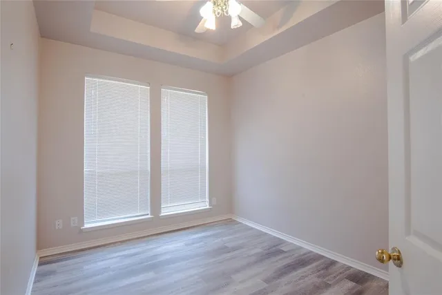 a view of an empty room with window and wooden floor