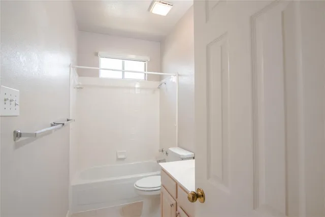 a bathroom with a granite countertop bathtub shower sink vanity and toilet