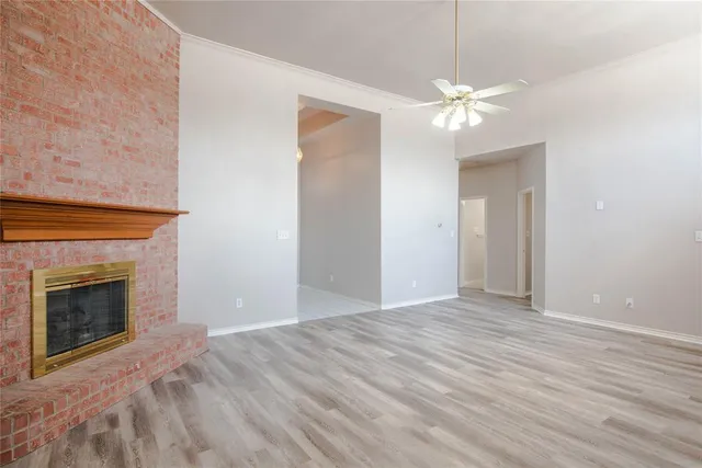 a view of an empty room with chandelier fan and fire place