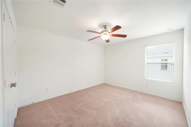 an empty room with a window and a fan