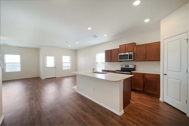 a kitchen with stainless steel appliances granite countertop a stove top oven a sink dishwasher a refrigerator and a microwave oven on the wooden floor
