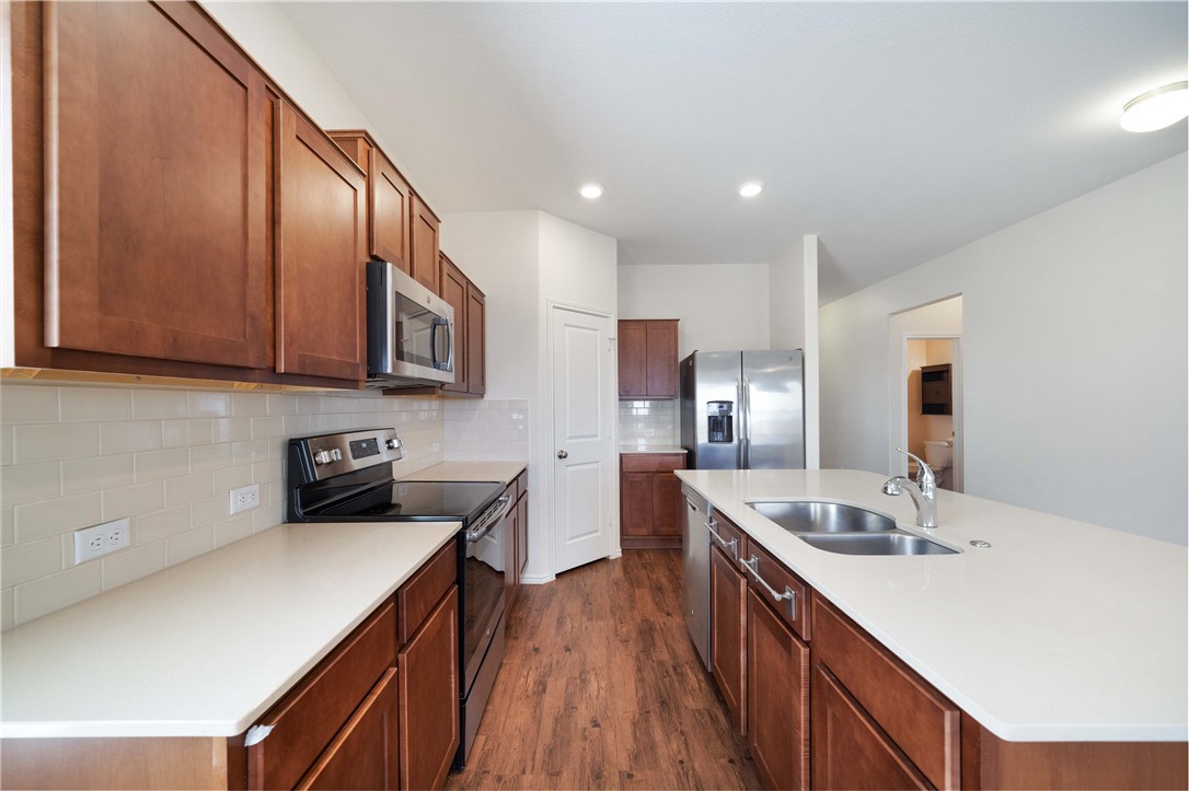 820 Kates Way Hutto, TX 78634 - Photo 8 of 30 a kitchen with stainless steel appliances granite countertop wooden cabinets a sink and dishwasher