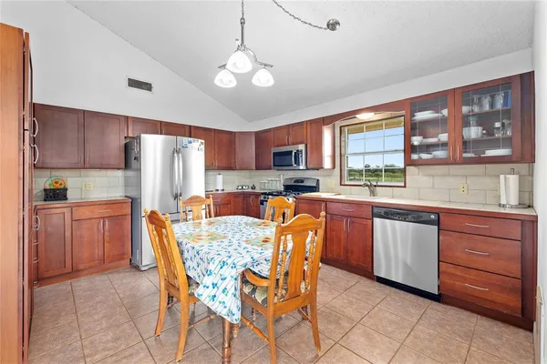 a kitchen with stainless steel appliances granite countertop a stove a refrigerator a sink dishwasher a dining table and chairs with wooden floor