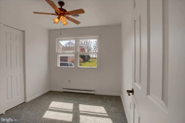 a view of an empty room and chandelier fan