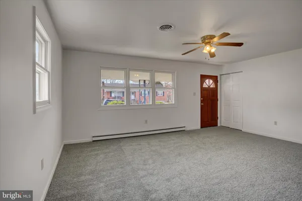 an empty room with windows and ceiling fan