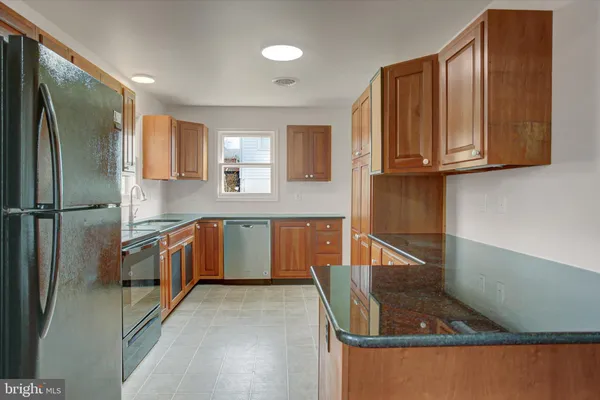 a kitchen with stainless steel appliances granite countertop a refrigerator a stove and a sink with wooden floor
