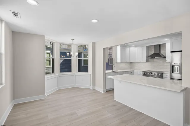 a large white kitchen with kitchen island a sink a stove and a refrigerator