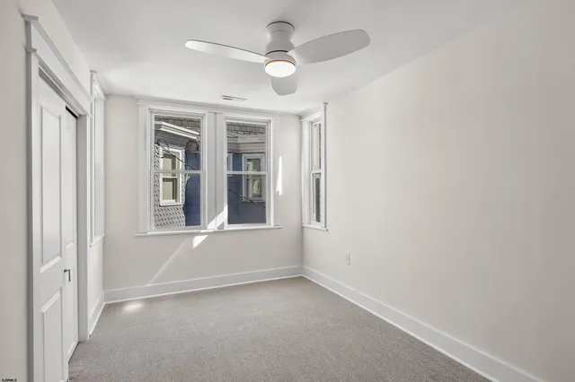 an empty room with windows and fan