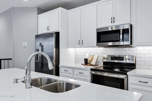 a kitchen with stainless steel appliances white cabinets a stove and a sink
