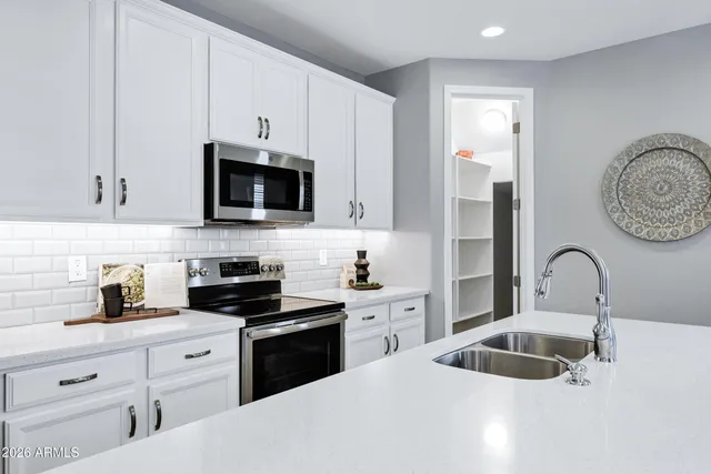 a kitchen with white cabinets a sink stove and microwave