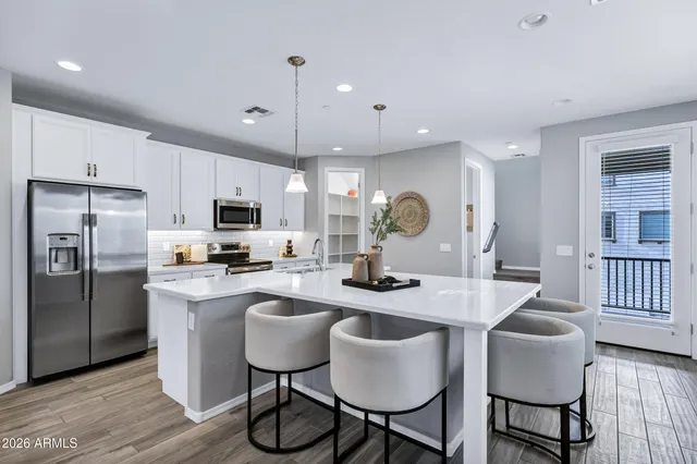 a kitchen with stainless steel appliances granite countertop a table chairs refrigerator and microwave