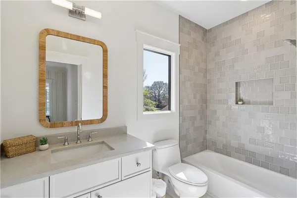 a bathroom with a granite countertop sink toilet a large mirror a bathtub and shower