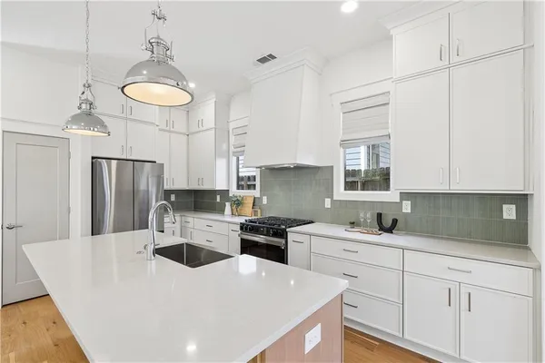 a kitchen with stainless steel appliances a sink a stove a refrigerator cabinets and a window