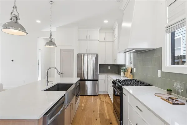 a kitchen with a sink dishwasher a refrigerator and cabinets with wooden floor