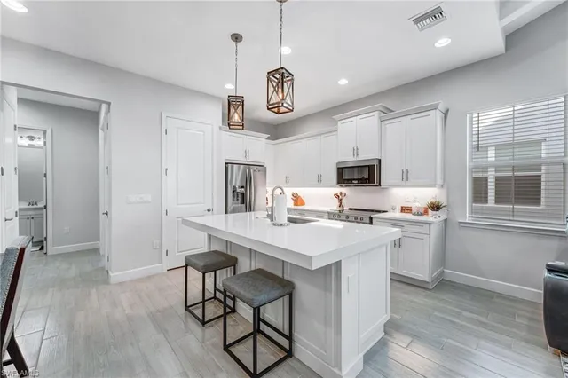 a kitchen with stainless steel appliances a kitchen island hardwood floor sink stove and wooden cabinets