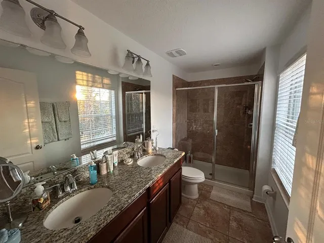 a bathroom with a granite countertop sink toilet a mirror a vanity and shower