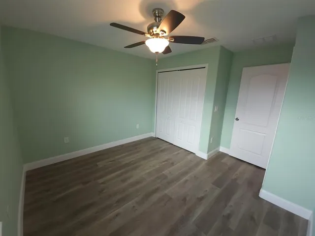 an empty room with wooden floor and fan