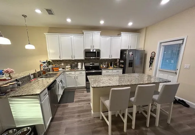 a kitchen with stainless steel appliances granite countertop a stove top oven a sink dishwasher a dining table and chairs