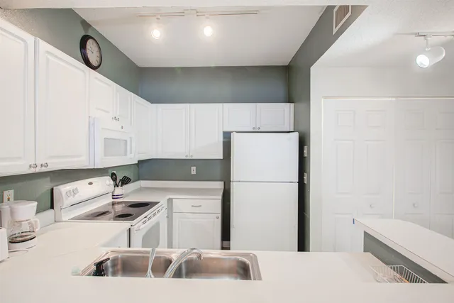 a kitchen with a sink a refrigerator and cabinets