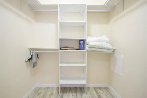 a walk in closet with wooden floor