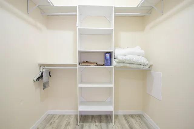 a walk in closet with wooden floor