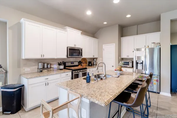 a kitchen with granite countertop a stove a sink a dining table and chairs