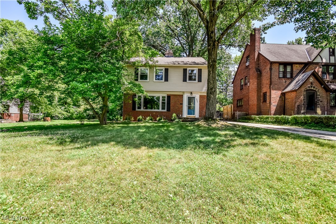 Colonial home with brick siding, a front lawn, and a chimney