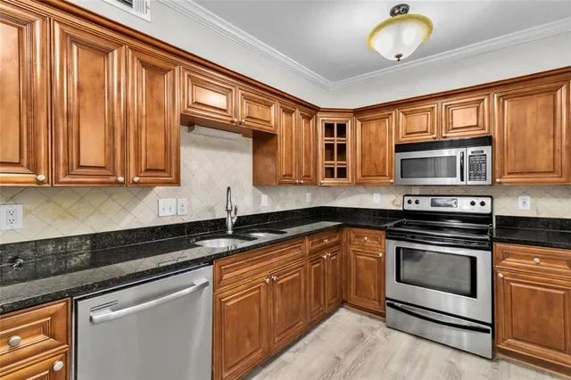 a kitchen with stainless steel appliances granite countertop wooden cabinets and a stove top oven