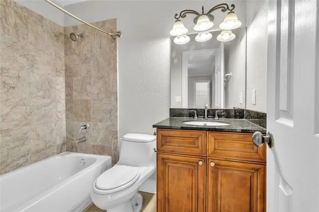 a bathroom with a granite countertop sink a toilet and a bathtub