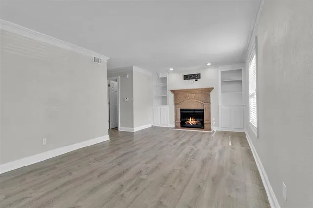 a view of an empty room with wooden floor fireplace and a window