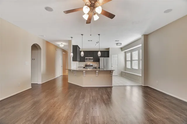 a view of a kitchen with kitchen island a island wooden floor stainless steel appliances and a window