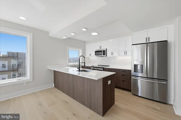 a kitchen with stainless steel appliances granite countertop a refrigerator a sink dishwasher a stove and a refrigerator