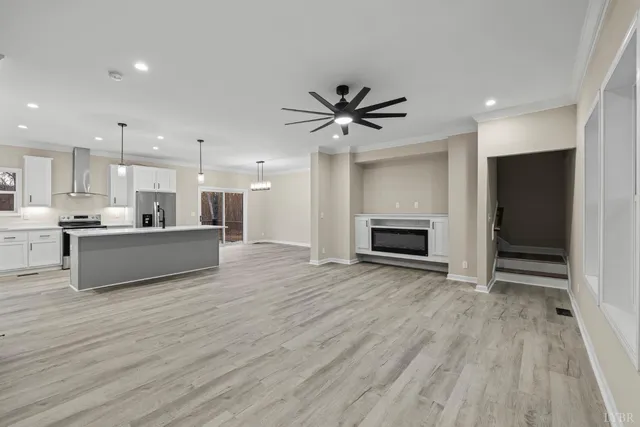 an empty room with wooden floor chandelier fan and windows