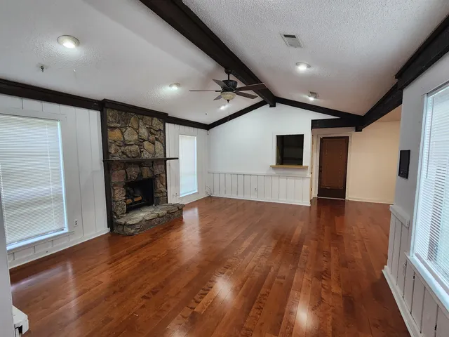 a view of empty room with wooden floor and fireplace