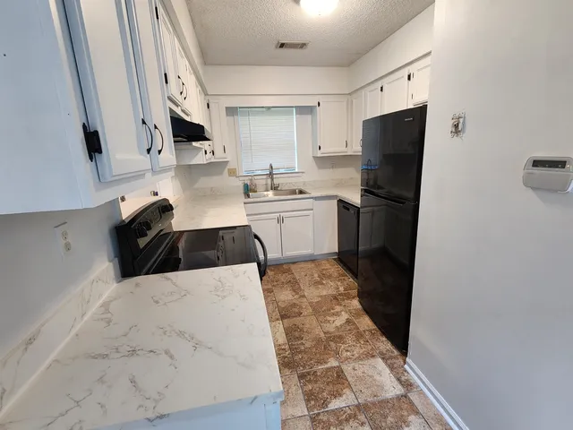 a kitchen with a sink a refrigerator and cabinets