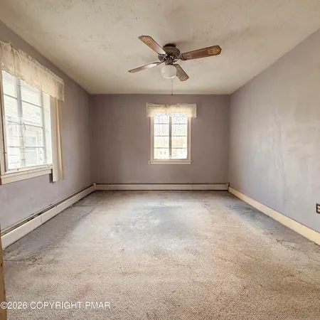 an empty room with a window and a ceiling fan