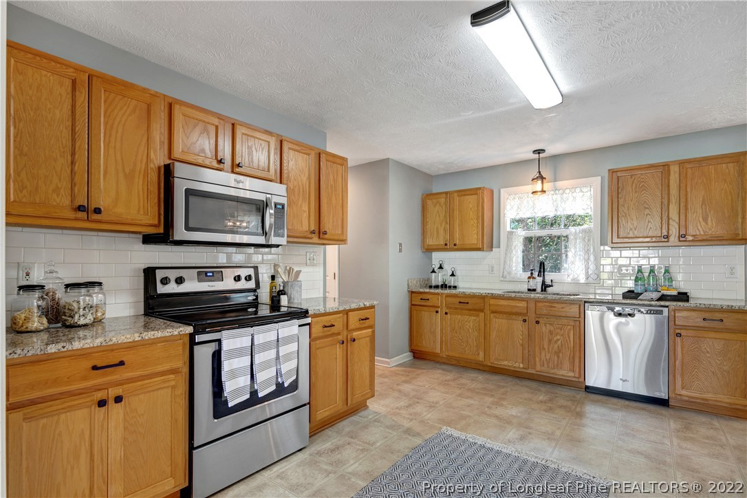 5823 Spreading Branch Road Hope Mills, NC 28348 - Photo 17 of 49 a kitchen with stainless steel appliances granite countertop a stove sink microwave and window