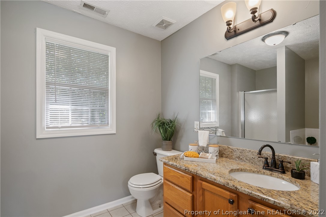 5823 Spreading Branch Road Hope Mills, NC 28348 - Photo 28 of 49 a bathroom with a granite countertop sink a toilet and mirror