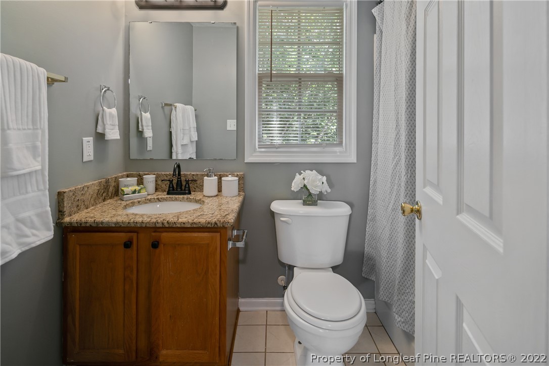 5823 Spreading Branch Road Hope Mills, NC 28348 - Photo 35 of 49 a bathroom with a granite countertop toilet a sink and a mirror