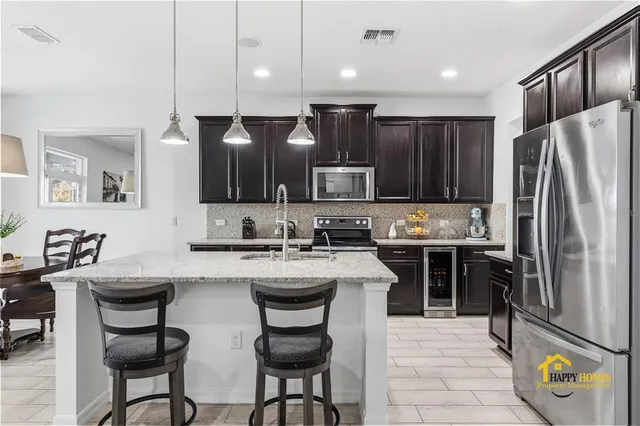 a kitchen with stainless steel appliances granite countertop a stove top oven a sink dishwasher a dining table and chairs with wooden floor