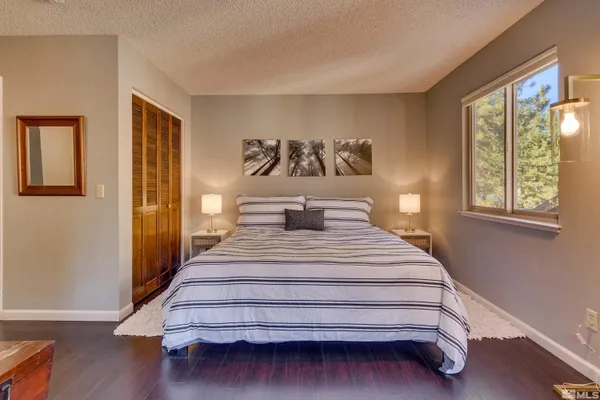 a spacious bedroom with a bed and wooden floor