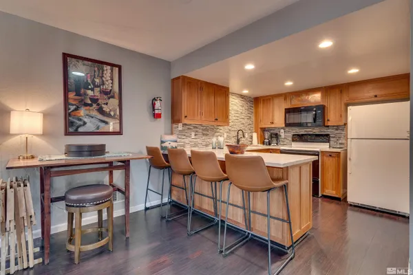 a kitchen with stainless steel appliances granite countertop a refrigerator a stove a sink a dining table and chairs with wooden floor