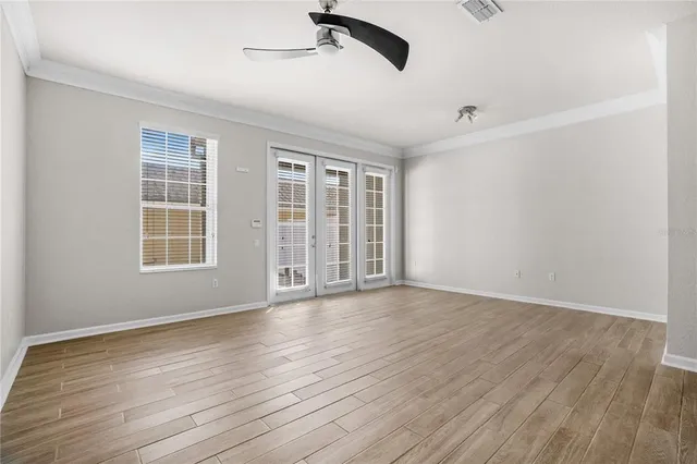a view of an empty room with wooden floor and a window