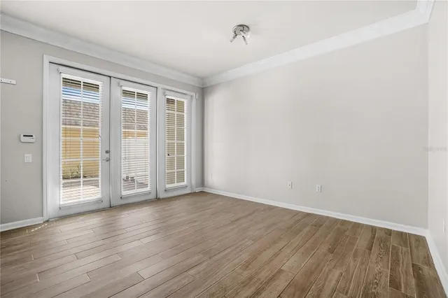 an empty room with wooden floor and windows