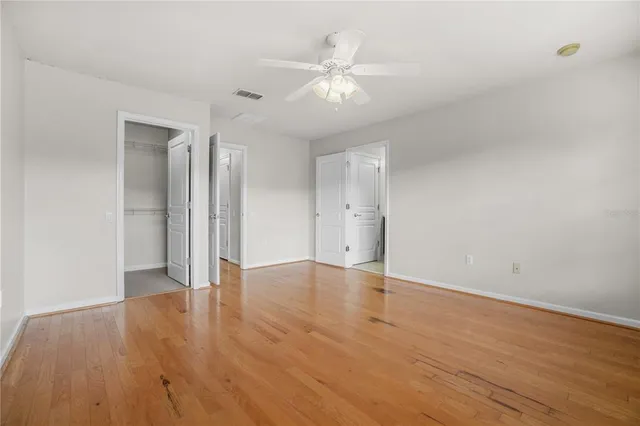 an empty room with wooden floor and ceiling fan