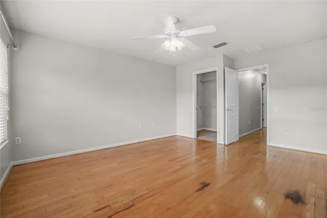 an empty room with wooden floor and fan